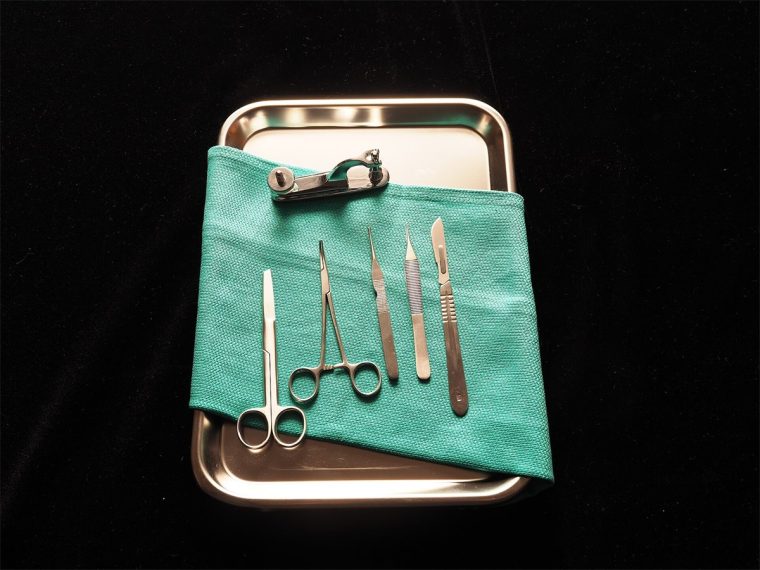 Vassoio sterile con forbici, pinza emostatica, pinzette e bisturi per un intervento in anestesia locale